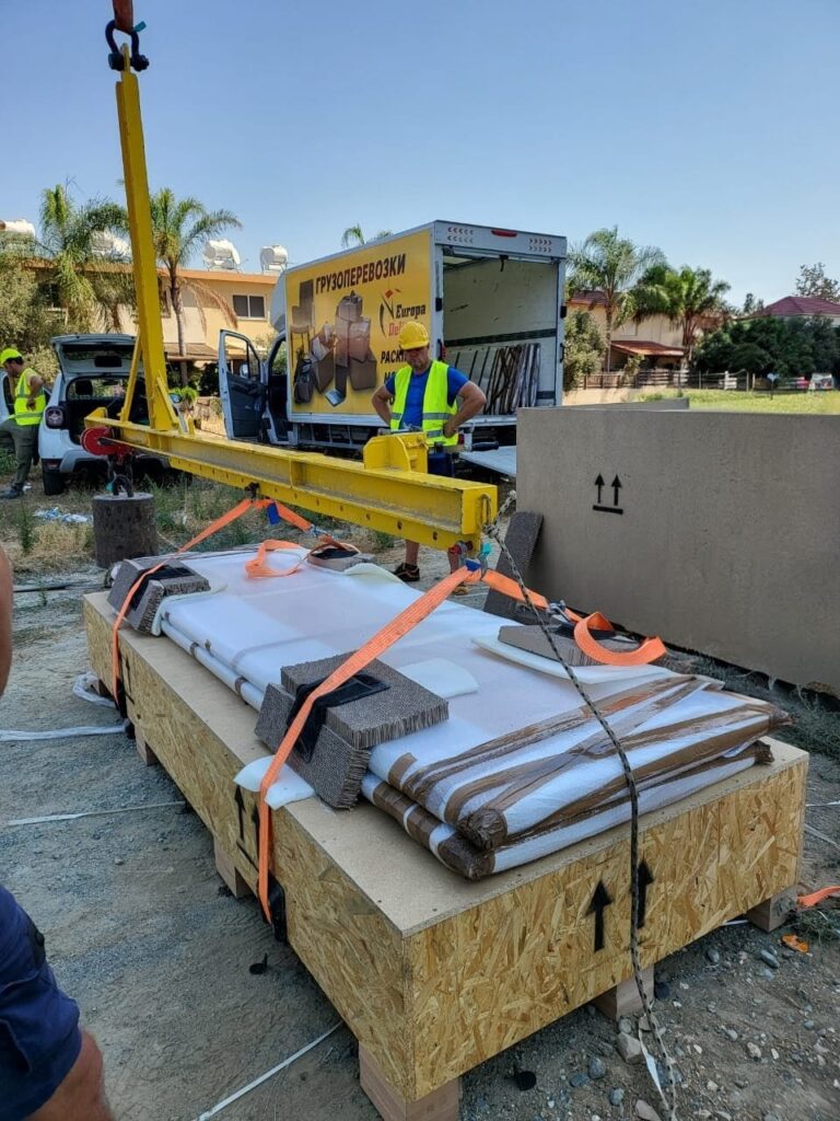 Europa Delivery ground crew rigging a large furniture crate for a crane lift outside a residential property
