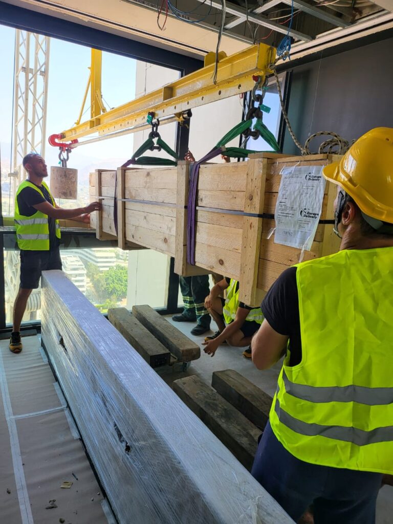 Professional movers from Europa Delivery safely detaching a suspended crate inside an Only Tower apartment.