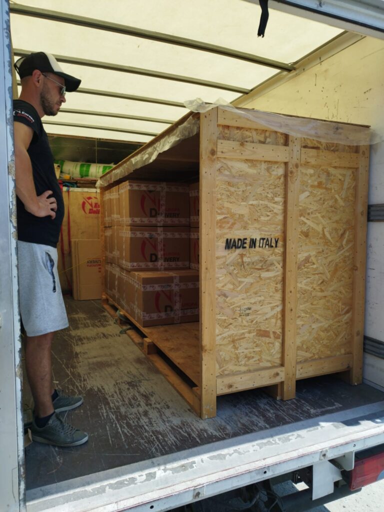 A professional logistics specialist inspecting perfectly stacked moving boxes secured inside a custom wooden crate for an international move.