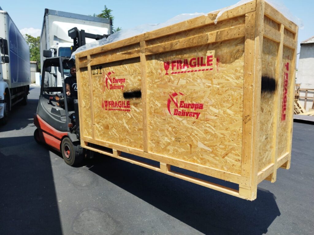 A forklift carefully transporting a large, custom-built wooden crate marked "FRAGILE" during a secure relocation from Cyprus to Spain